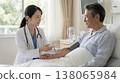 A female doctor talking to a hospitalized patient in their room. 138065984
