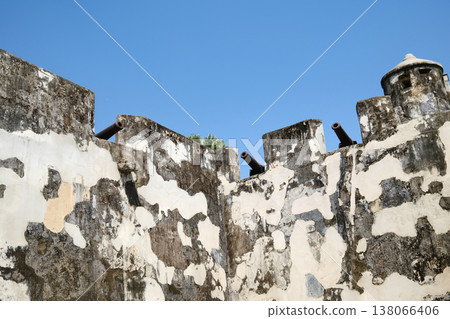 Ruined ancient fortress stone walls with cannons on top against blue sky in Macau Monte Fort heritage site Ruined ancient fortress stone walls with cannons on top against blue sky in Macau Monte Fort heritage site 138066406