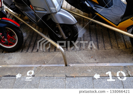Parked scooter motorcycle with road markings and railing in Macau urban street scene Parked scooter motorcycle with road markings and railing in Macau urban street scene 138066421