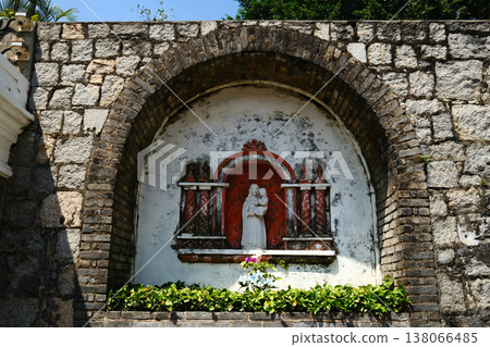 Stone arch niche with religious Virgin Mary statue shrine on ancient fortress wall in Macau heritage site Stone arch niche with religious Virgin Mary statue shrine on ancient fortress wall in Macau heritage site 138066485