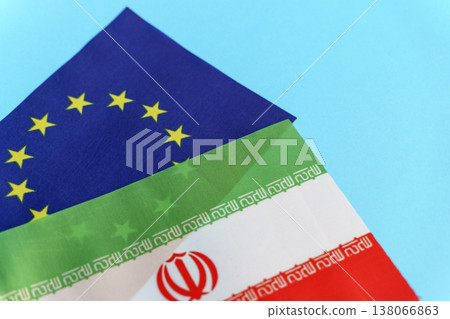 Flags of the European Union and Iran symbols isolated on an empty blue background. Conceptual photography showing international relations and foreign policy discussions between the EU and the Islamic 138066863