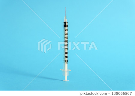 Medical insulin syringe with needle isolated on a vibrant blue background. A close-up studio shot of a sterile disposable syringe used for injections, healthcare, and diabetes treatment. Medical insulin syringe with needle isolated on a vibrant blue background. A close-up studio shot of a sterile disposable syringe used for injections, healthcare, and diabetes treatment. 138066867