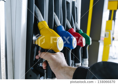 Fuel pump nozzles hanging at a modern gas station during a period of high oil prices. A conceptual photography showcasing the global energy crisis, increasing gasoline costs Fuel pump nozzles hanging at a modern gas station during a period of high oil prices. A conceptual photography showcasing the global energy crisis, increasing gasoline costs 138066870