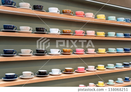 Colorful Stacks of Ceramic Mugs and Plates including yellow, pink, blue and white on Wooden Shelves. Colorful Stacks of Ceramic Mugs and Plates including yellow, pink, blue and white on Wooden Shelves. 138068251