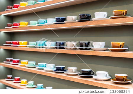 Colorful Stacks of Ceramic Mugs and Plates including yellow, red, blue, and white on Wooden Shelves. Colorful Stacks of Ceramic Mugs and Plates including yellow, red, blue, and white on Wooden Shelves. 138068254