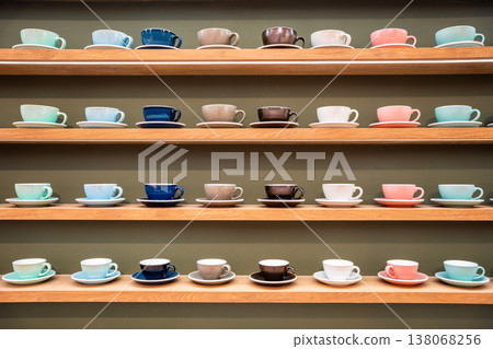 Colorful Stacks of Ceramic Mugs and Plates including brown, pink, blue and white on Wooden Shelves. 138068256