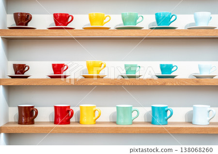Colorful Ceramic Coffee Cups including red, yellow, green, cyan, black and white Displayed on Wooden Shelves in Store. Colorful Ceramic Coffee Cups including red, yellow, green, cyan, black and white Displayed on Wooden Shelves in Store. 138068260