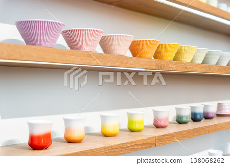 Variety of colorful ceramic pottery bowls and Japanese tea cup mugs displayed on wooden shelves. Variety of colorful ceramic pottery bowls and Japanese tea cup mugs displayed on wooden shelves. 138068262