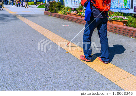 在日本橫濱的城市景觀中,一位拄著白色盲杖(視障人士安全盲杖)的老人正在街區行走…= 橫濱市(櫻木町站前) 在日本橫濱的城市景觀中,一位拄著白色盲杖(視障人士安全盲杖)的老人正在街區行走…= 橫濱市(櫻木町站前) 138068346