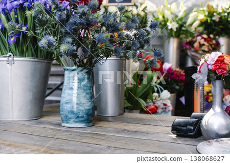 Cozy and authentic rustic flower shop counter with dried lavender and vintage gardening tools. An intimate workshop scene showing a hand tying a flower bouquet on a weathered wooden table with antique Cozy and authentic rustic flower shop counter with dried lavender and vintage gardening tools. An intimate workshop scene showing a hand tying a flower bouquet on a weathered wooden table with antique 138068627