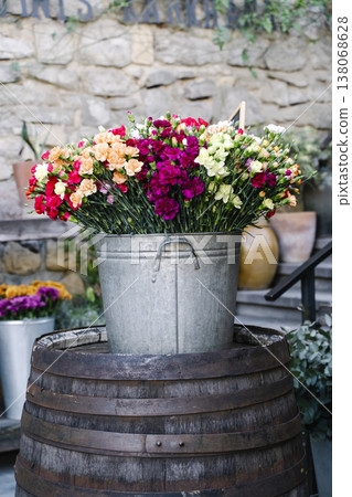 Colorful Carnation Bouquets in Metal Bucket on Rustic Barrel at Flower Market Colorful Carnation Bouquets in Metal Bucket on Rustic Barrel at Flower Market 138068628