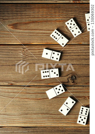 People play a game with white dominoes on a wooden table in the afternoon 138069302