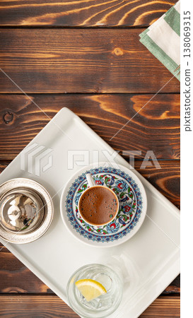 Turkish coffee served on a tray with water and lemon on a wooden table Turkish coffee served on a tray with water and lemon on a wooden table 138069315