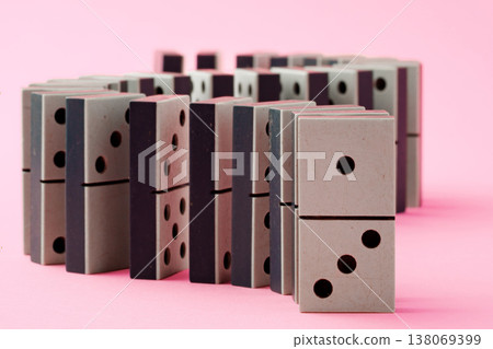 Dominoes arranged in a line with a pink background in a simple setting 138069399