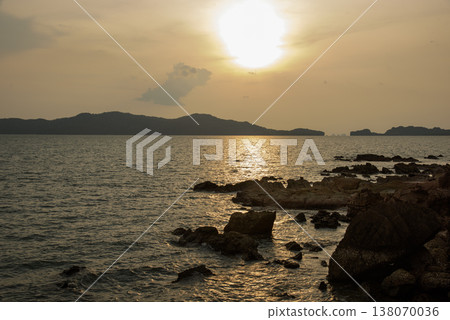 Landscape with sunset at the seashore. sunset sea rock horizon view. Sea rock sunset silhouette. Sunset sea rock and mountain range. Nature background 138070036