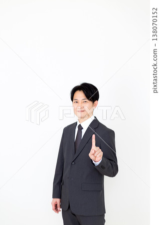 A middle-aged businessman holding up his index finger. 138070152