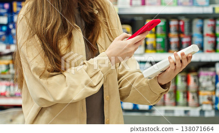 Woman Scanning Pet Shampoo With Smartphone And Checking Product Information, Reviews And Price In Store Before Purchase. Pet Care And Smart Shopping Concept. 138071664
