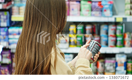 Woman Reading Canned Pet Food Label In Supermarket, Checking Ingredients And Product Information Before Purchase. Pet Care And Retail Shopping Concept. Woman Reading Canned Pet Food Label In Supermarket, Checking Ingredients And Product Information Before Purchase. Pet Care And Retail Shopping Concept. 138071672