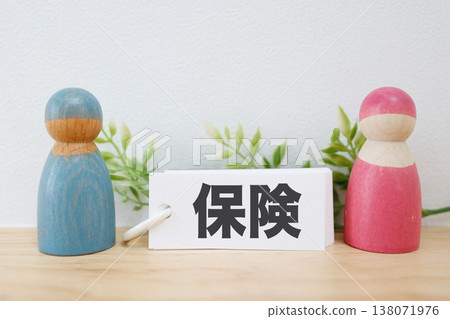 A simple composition featuring wooden figures and cards representing a married couple and insurance. A simple composition featuring wooden figures and cards representing a married couple and insurance. 138071976