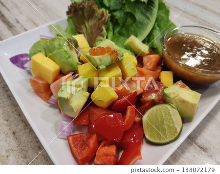 Fresh Salmon Thai Style Salad with Avocado, Mango, Bell Peppers, Lettuce, Lime, and Spicy Thai Dressing on a White Plate Fresh Salmon Thai Style Salad with Avocado, Mango, Bell Peppers, Lettuce, Lime, and Spicy Thai Dressing on a White Plate 138072179