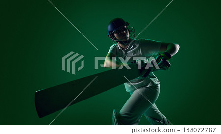 Female cricket batter swinging bat in powerful hit action in green studio lighting. 138072787