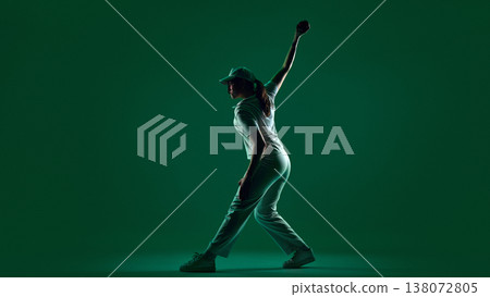 Female cricket player walking forward holding ball in minimal green studio lighting. Female cricket player walking forward holding ball in minimal green studio lighting. 138072805