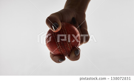 Extreme close up cricket ball in female hand isolated on white background. Extreme close up cricket ball in female hand isolated on white background. 138072831