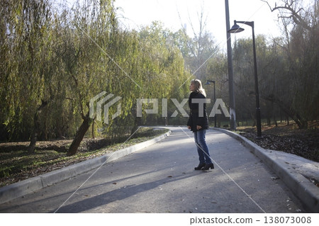 A young woman walks through the autumn park. A young woman walks through the autumn park. 138073008