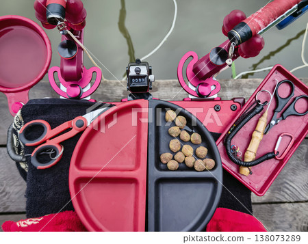Fishing setup with tools and bait on a wooden dock during the day near a calm water body 138073289