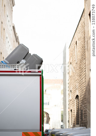 Moving truck carrying containers through a narrow European city alley, navigating historic urban streets surrounded by old brick buildings, suggesting a scene of transport and relocation 138073749