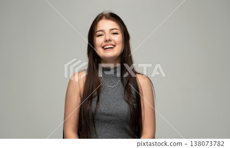 Young woman confidently smiling and laughing, expressing happiness and cheerful emotion while posing in a studio 138073782