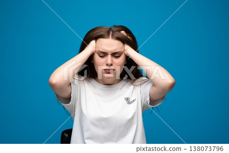 Young woman suffering from intense headache or migraine, feeling stressed, tired, frustrated, clutching head in pain 138073796