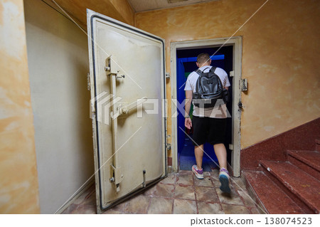 Man With Backpack Entering Hidden Vault Doorway In Old Building Stairwell For Urban Exploration 138074523