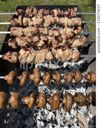 Close-up from above showing fresh meat being grilled on metal skewers. 138074637