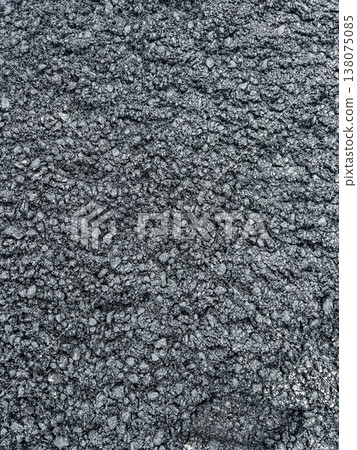 Texture of rough black asphalt road surface. Close up view of bitumen pavement with small stone gravel. Abstract background pattern for construction industry and urban infrastructure design. Texture of rough black asphalt road surface. Close up view of bitumen pavement with small stone gravel. Abstract background pattern for construction industry and urban infrastructure design. 138075085