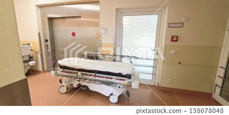 Hospital corridor with empty patient bed near elevator and door 138078048