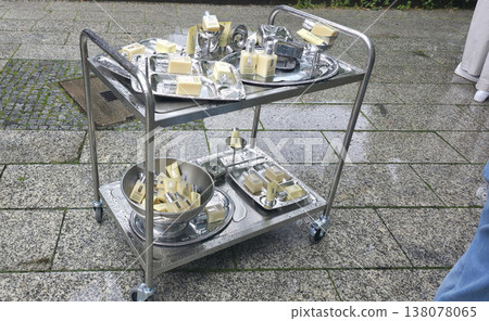 Berlin, Germany - July 17, 2025: Metal serving cart with soap bars and trays on wet stone pavement Berlin, Germany - July 17, 2025: Metal serving cart with soap bars and trays on wet stone pavement 138078065