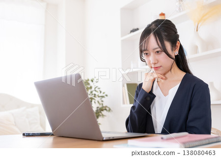 A woman in her 20s with a troubled expression while looking at her computer. 138080463