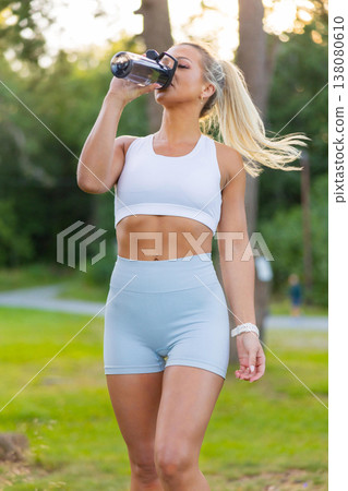 Young woman enjoying outdoor fitness while hydrating during a workout 138080610