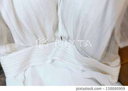 Textured ivory bridal gown waist detail with shimmering belt and pleats 138080909