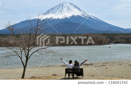 一對情侶凝視著富士山和湖泊；他們背對著鏡頭，欣賞著令人嘆為觀止的美景。 138081342