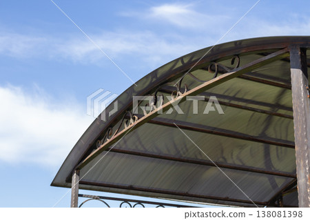 Protective metal shelter with translucent arched roof panels ornate scrollwork details,covered parking or patio cover structure Protective metal shelter with translucent arched roof panels ornate scrollwork details,covered parking or patio cover structure 138081398