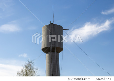 Cylindrical concrete water tower structure with ladder, blue base, outdoors 138081864