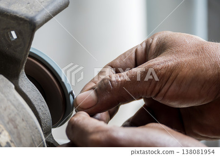 Professional operator performing a precision small drill tool regrind process using an abrasive grinding wheel. Professional operator performing a precision small drill tool regrind process using an abrasive grinding wheel. 138081954