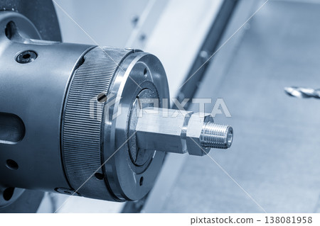 Mass production of precision metal threaded parts using an automated CNC lathe machine in an industrial setting. Mass production of precision metal threaded parts using an automated CNC lathe machine in an industrial setting. 138081958