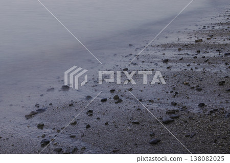 一片潮濕的沙灘，散落著鵝卵石。 138082025