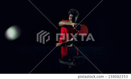 Table tennis player hitting ball with powerful stroke in dark studio. Table tennis player hitting ball with powerful stroke in dark studio. 138082353