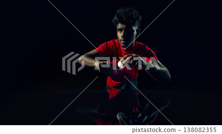 Table tennis player preparing serve in dark studio with reflection surface Table tennis player preparing serve in dark studio with reflection surface 138082355