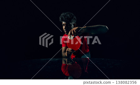 Table tennis player competing for point in dark studio with reflection surface. Table tennis player competing for point in dark studio with reflection surface. 138082356