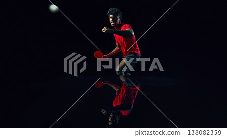 Table tennis player reacting to fast ball in dark studio with reflection surface. 138082359